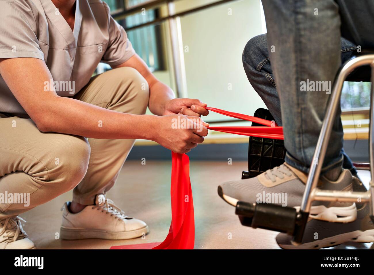 fisioterapeuta asiático joven trabajando con el hombre mayor en mejorar la fuerza de la pierna usando la banda de resistencia Foto de stock