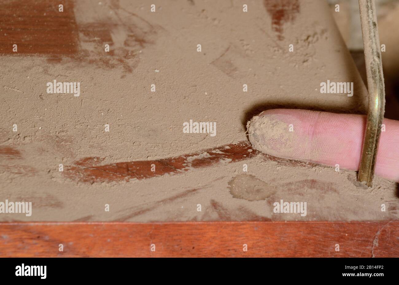 Polvo en un estante, un dedo ha dibujado una línea en el polvo y muestra la "captura" Foto de stock