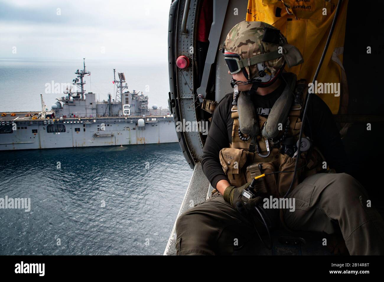 U.S. Navy Naval Aircrewman (helicóptero) 2 ª clase Tanner Brown, de Prescott Valley, Arizona, asignado a los Wildcards de helicóptero sea Combat Squadron (HSC) 23, mantiene comunicaciones con el piloto de un MH-60S sea Hawk helicóptero durante un reabastecimiento vertical en el mar con el buque anfibio de asalto USS Bonhomme Richard (LHD 6) En el Océano pacífico 26 de septiembre de 2018. Bonhomme Richard está operando en el área de operaciones de la 3ra flota. (EE.UU Foto de Marina por Especialista en Comunicación de masas Escudos Gavin de tercera clase) Foto de stock