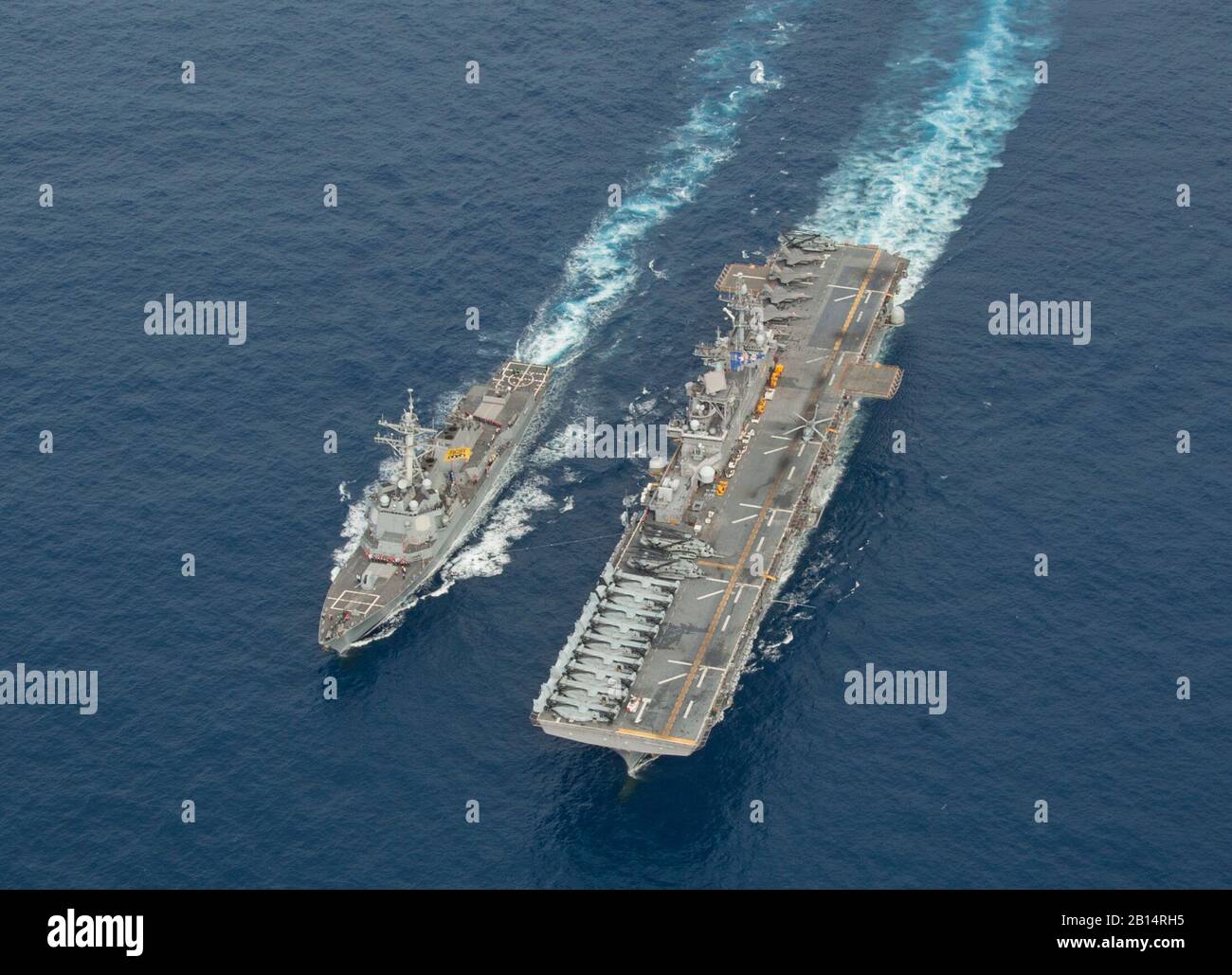 El destructor de misiles guiados USS Dewey (DDG 105), a la izquierda, recibe combustible del buque de asalto anfibio USS Wasp (LHD 1) durante un repostaje en el mar (FAS) en el Mar de Filipinas, el 12 de abril de 2018. El Wasp y su grupo de huelga expedicionaria (ESG) están operando en la región del Indo-Pacífico para mejorar la interoperabilidad con sus socios, sirven como fuerza de respuesta para cualquier tipo de contingencia y avanzan el concepto de ESG armado. (EE.UU Foto de la Marina por Especialista en Comunicación de masas 3 de clase Taylor King) Foto de stock