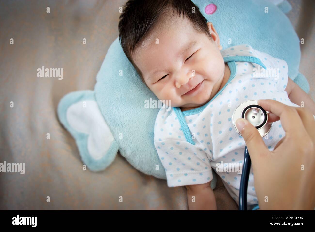 concepto de personas sanas. Bebé adorable asiático riendo con cara feliz para una buena salud en el tiempo de chequeo médico Foto de stock