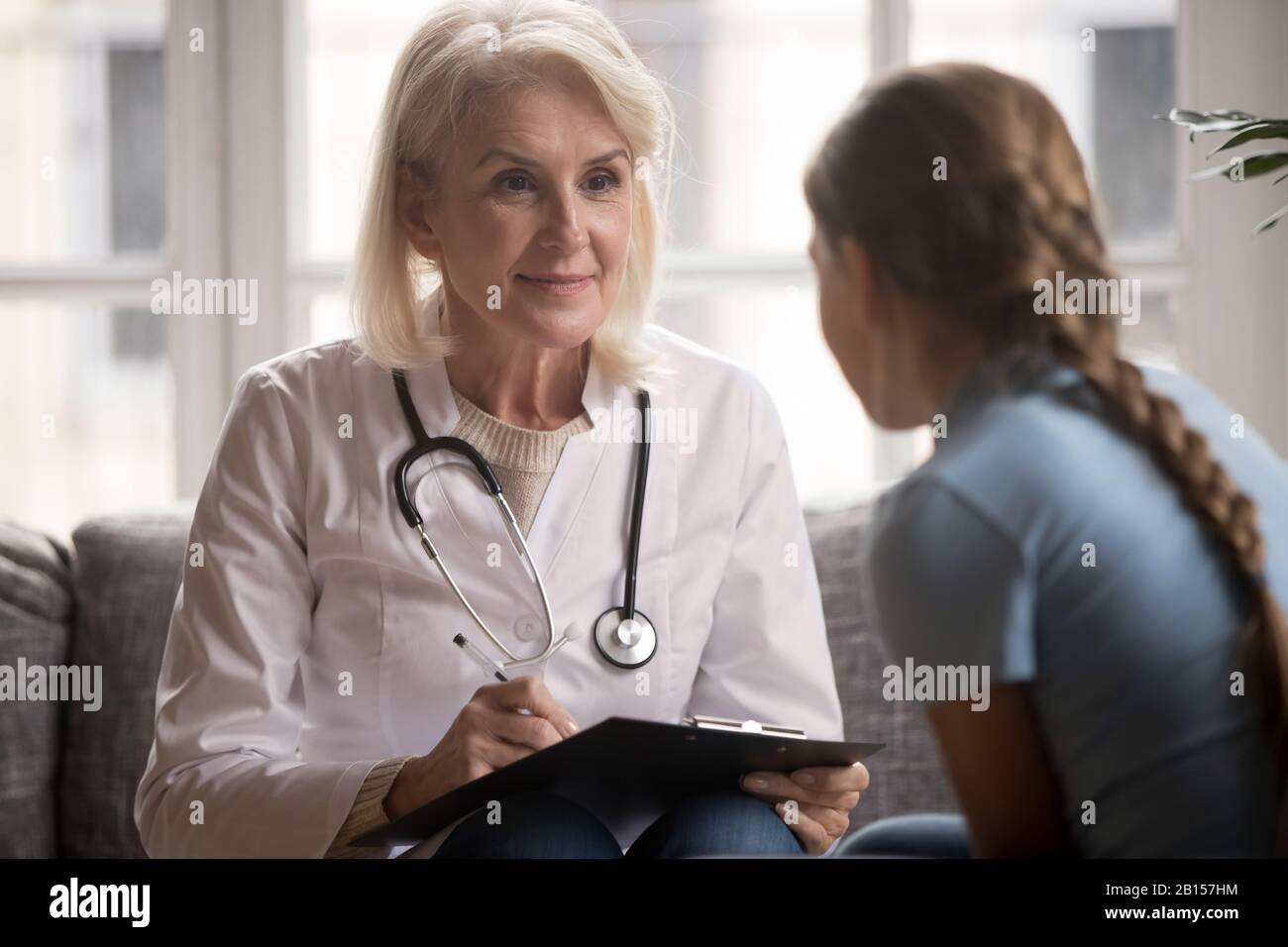 Pediatra agradable de mediana edad que escucha la queja de un paciente joven. Foto de stock
