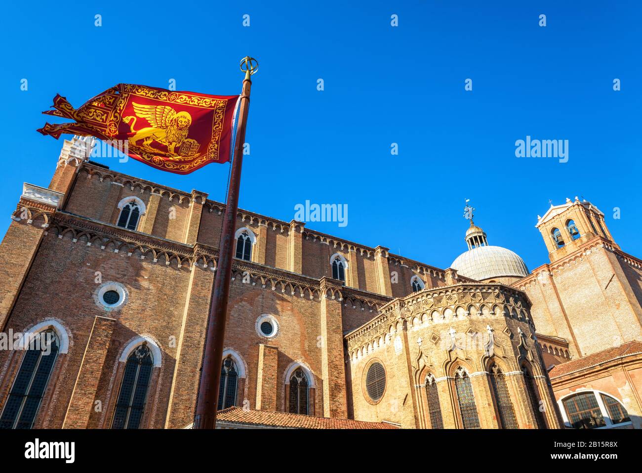 Bandera de Venecia cerca de la Basílica de San Giovanni e Paolo en Venecia, Italia. Esta antigua iglesia es uno de los principales monumentos de Venecia. Bandera roja veneciana w Foto de stock
