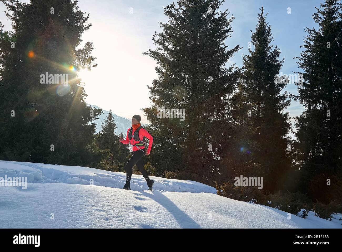 Corredor en chaqueta rosa mujer corriendo en invierno montaña camino en la nieve. Foto de stock