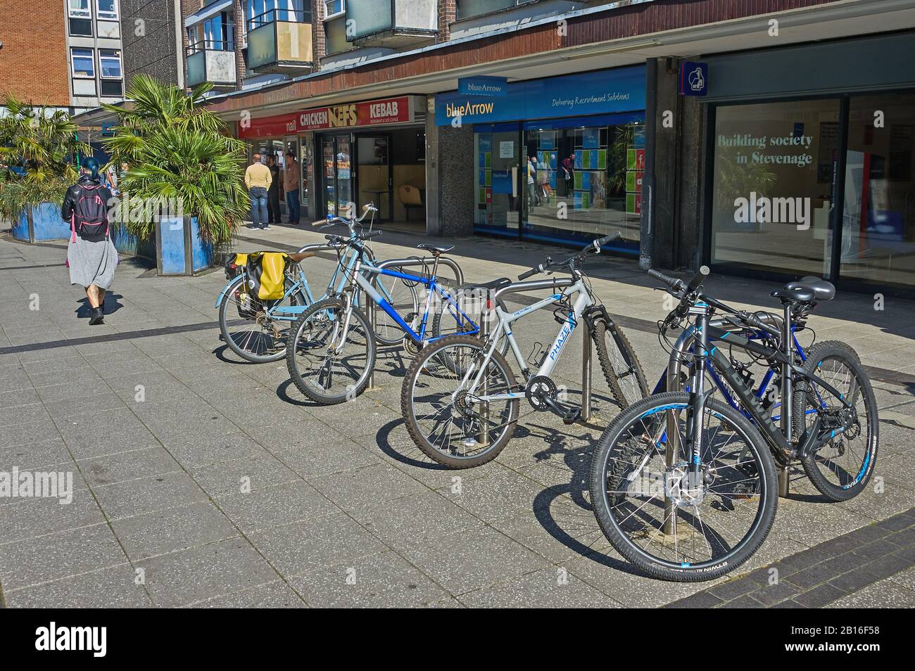 Bicicletas estacionadas en puestos de bicicletas fuera de las tiendas en el centro de Stevenage Foto de stock