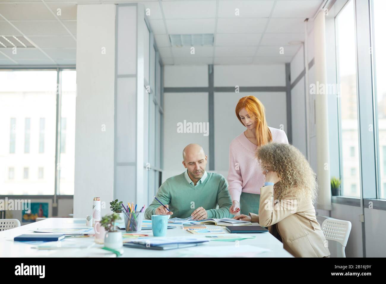 Grupo de tres personas de negocios que discuten documentos mientras trabajan en la mesa en la oficina, espacio de copia Foto de stock