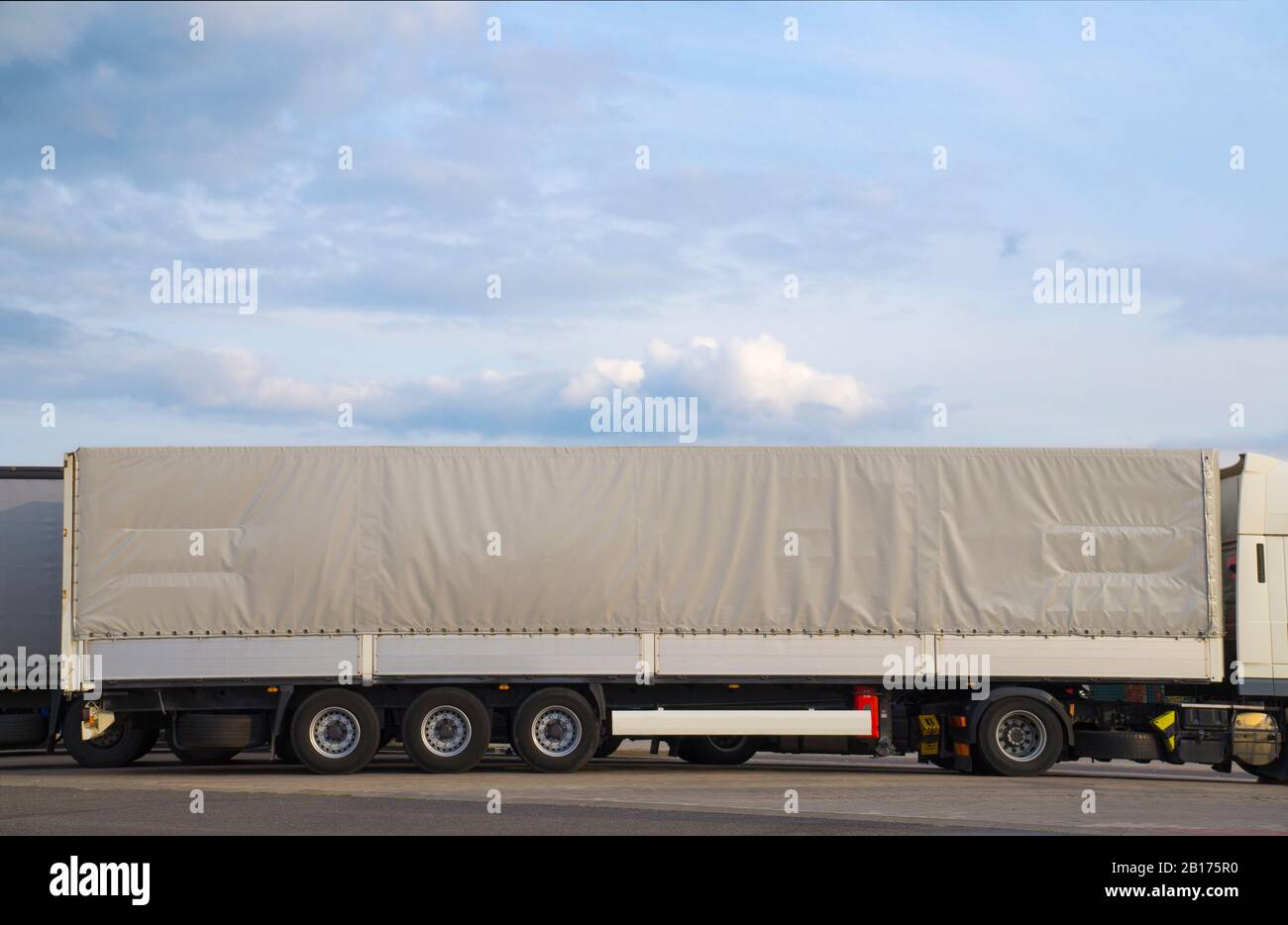 Un camión con un semirremolque largo cubierto con una lona gris. Camiones  en el estacionamiento Fotografía de stock - Alamy