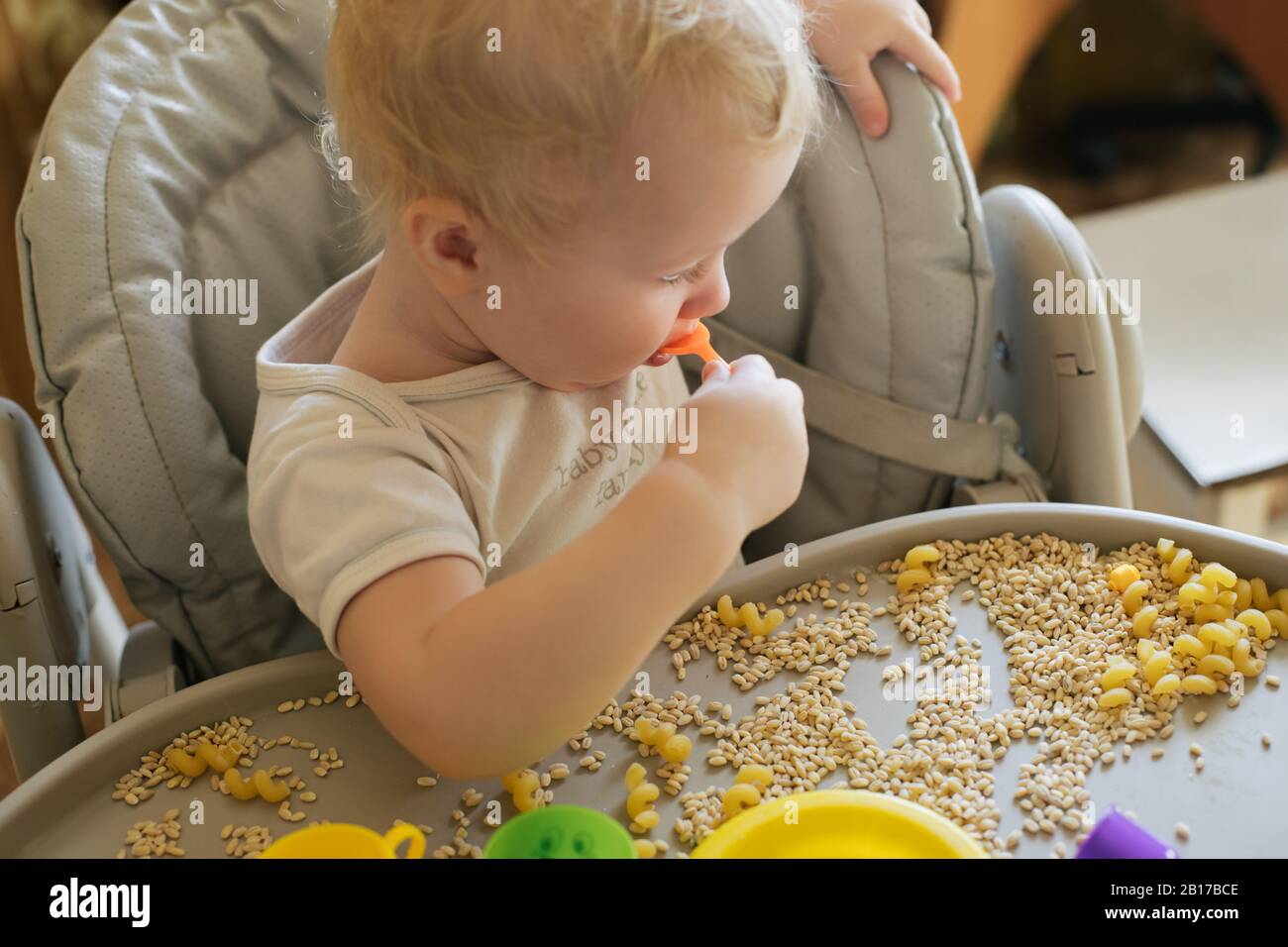 El niño come juguetes que se estropean de porridge. Desarrollo de habilidades motoras finas en niños hasta el año. Concepto desarrollo Temprano. Juguetes naturales Foto de stock