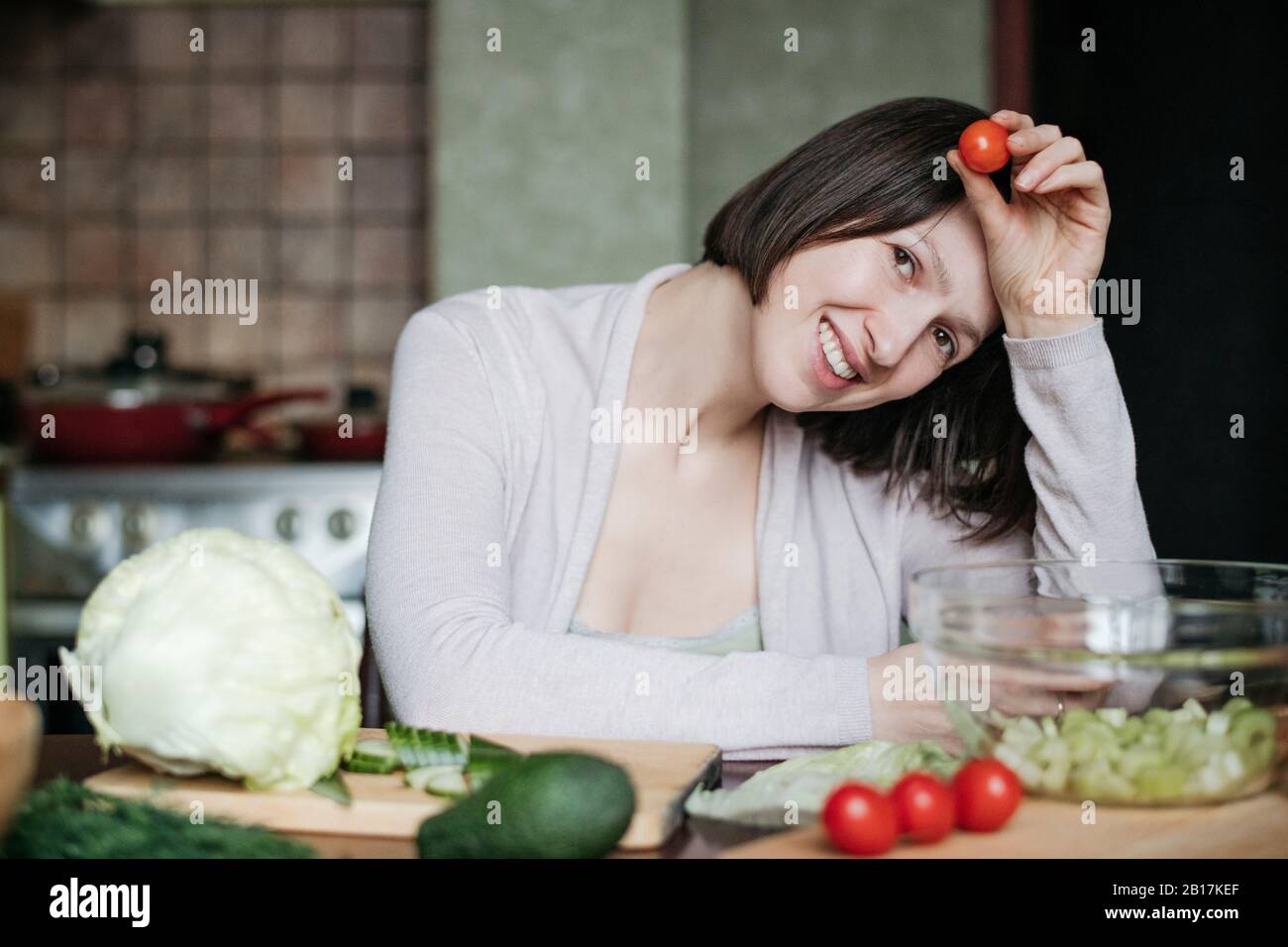 Retrato de una mujer feliz preparando ensalada en la cocina Foto de stock