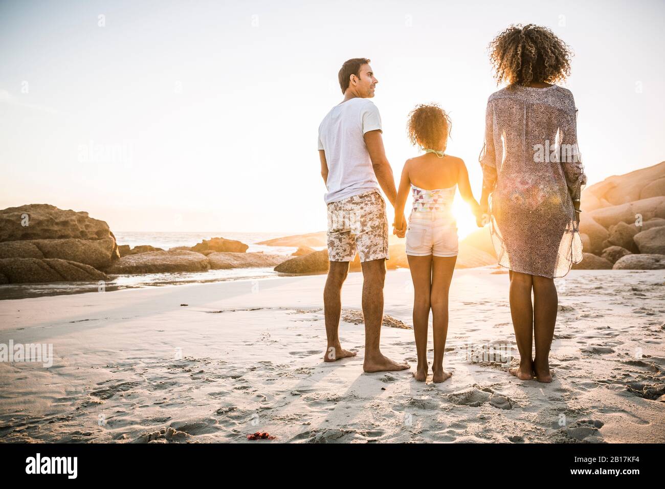 Familia disfrutando de la puesta de sol en la playa Foto de stock
