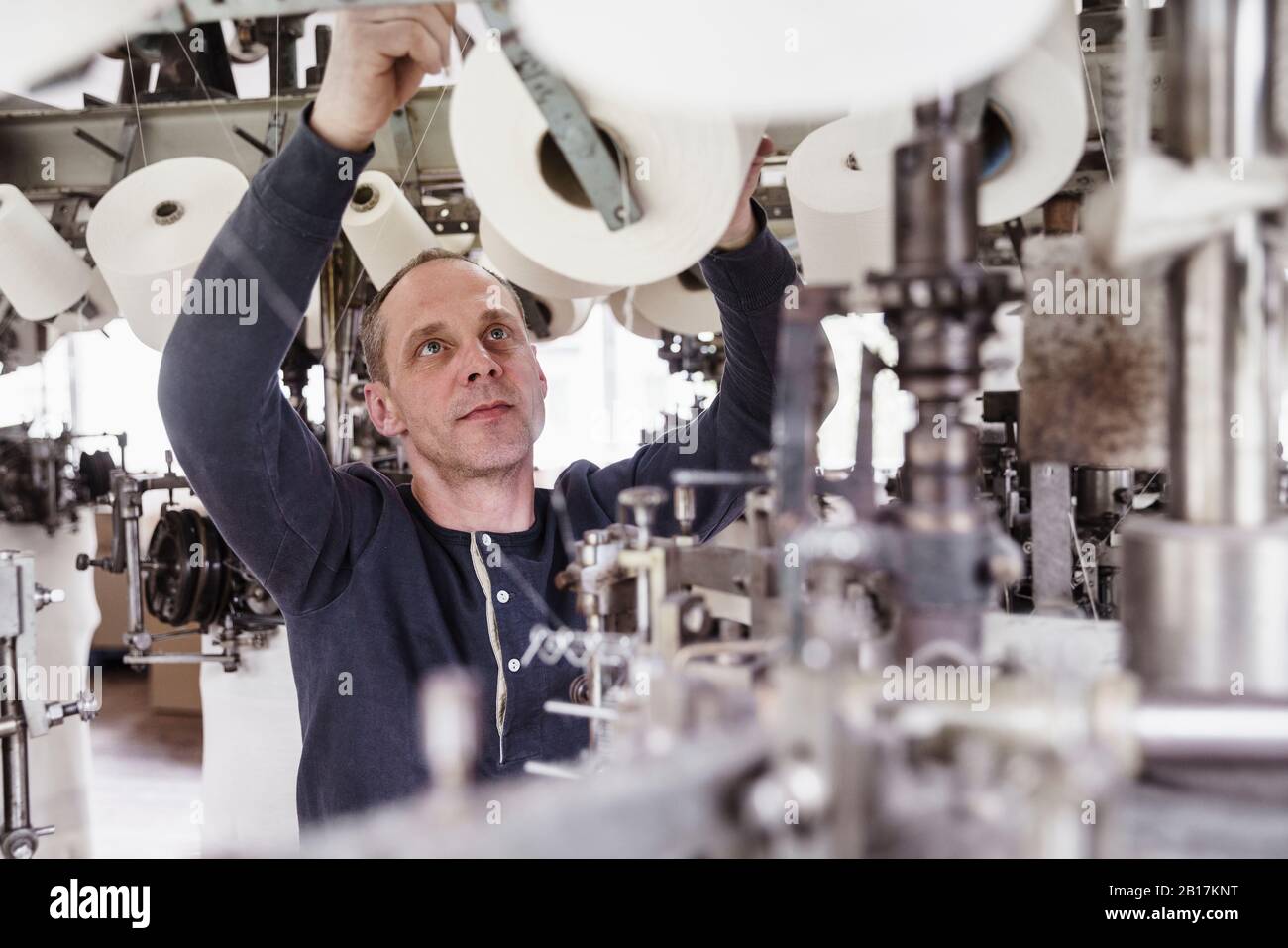 Hombre trabajando en una máquina en una fábrica textil Foto de stock