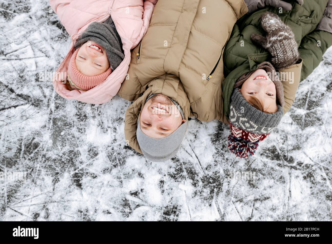Retrato familiar de padre y dos niños tumbados sobre hielo en invierno Foto de stock