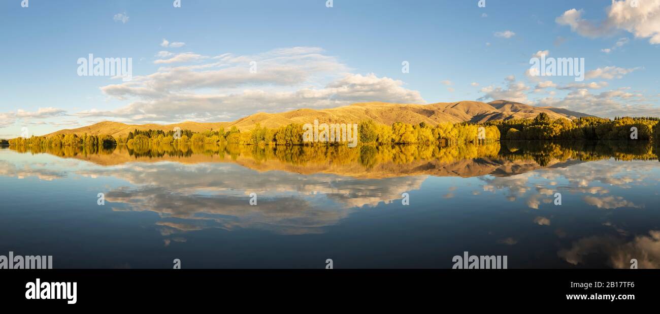 Nueva Zelanda, Distrito Franklin, Glenbrook, colinas boscosas que se reflejan en el lago Wairepo Arm en otoño Foto de stock