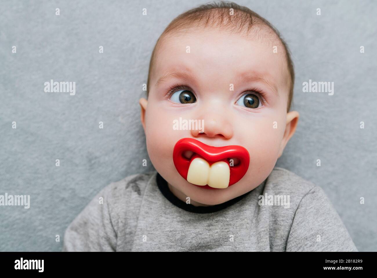 Retrato de niña con chupete de dientes grandes sobre manta gris Fotografía de - Alamy
