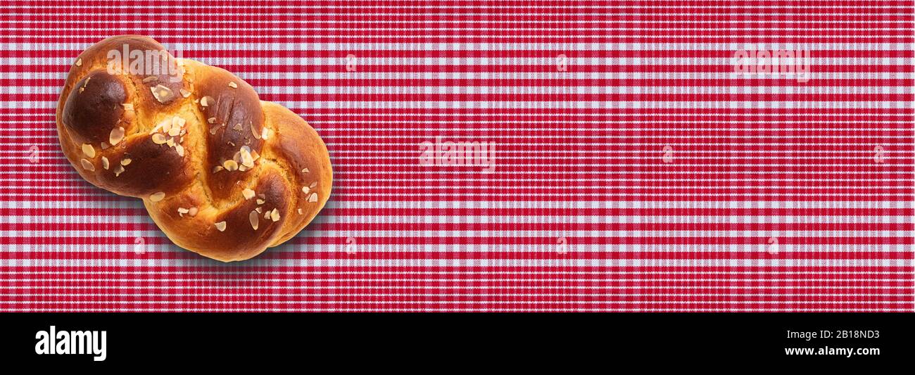 Pan dulce, tsoureki pascual, cozonac sobre fondo de mantel de cuadros rojos. Brioche trenzado, challah tradicional festivo. Banner, espacio de copia Foto de stock