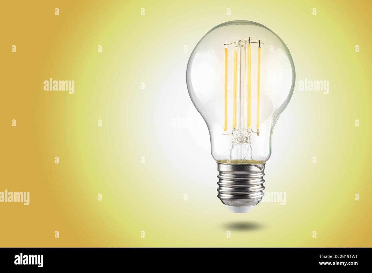 Bombilla LED de filamento con casquillo e27 sobre fondo amarillo. Foto de stock