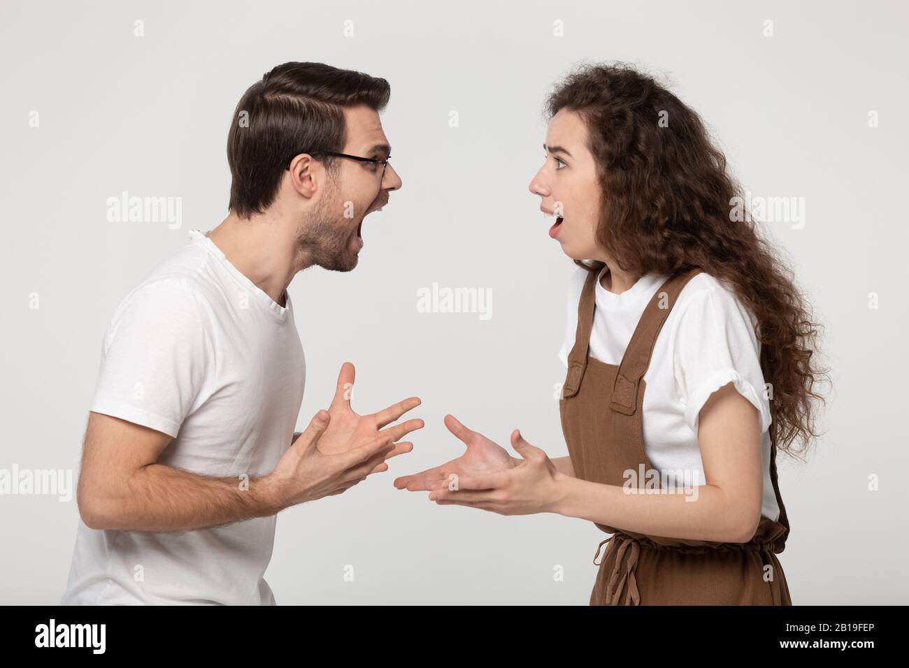 Agresivo estresó a la pareja joven discutiendo uno frente al otro. Foto de stock