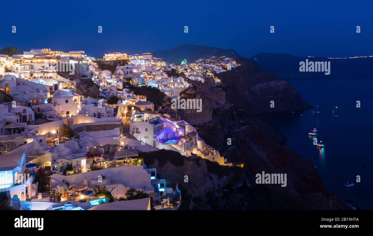 El pueblo de Oia en la isla de Santorini cobra vida al anochecer. Foto de stock