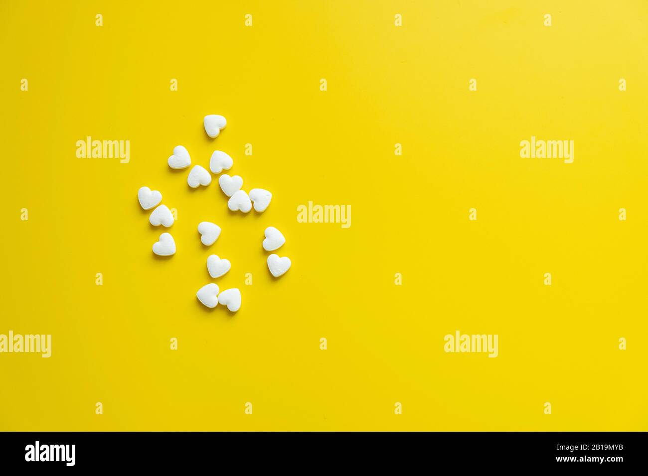 Píldoras blancas de cardiología sobre un fondo amarillo minimalismo, concepto de medicina Foto de stock