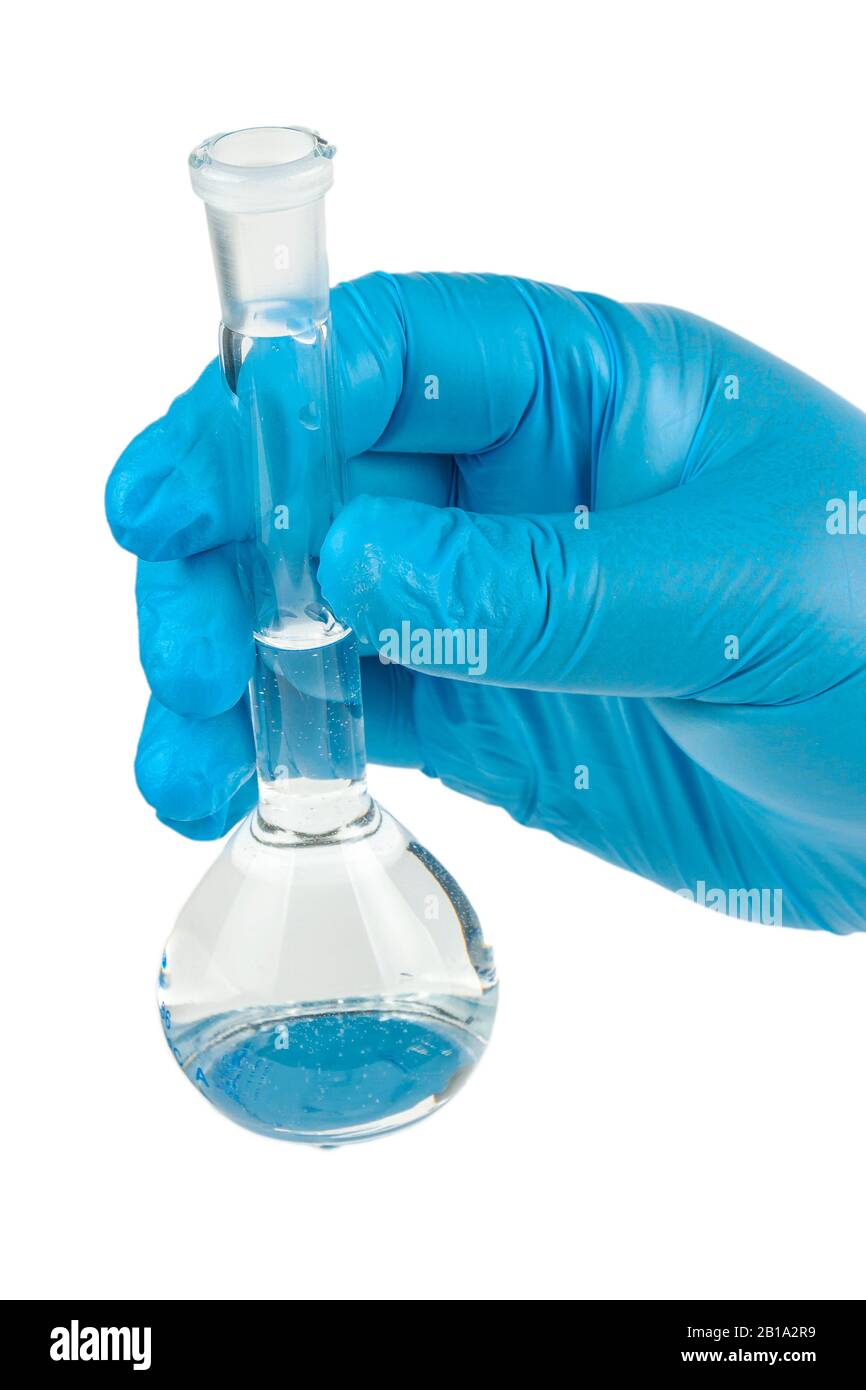 La mano sostiene un tubo de ensayo con agua sobre un fondo blanco. Foto de stock