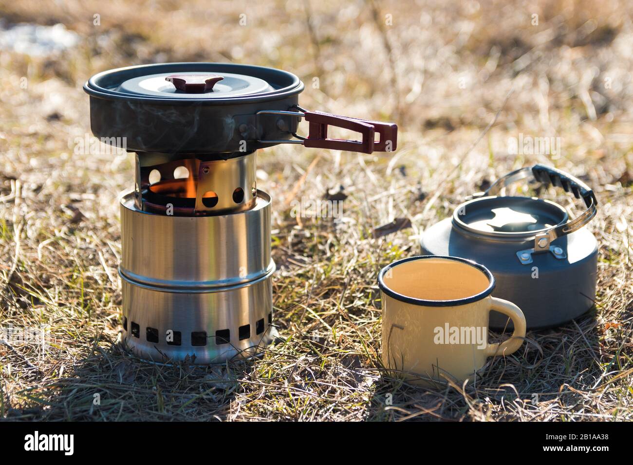 preparación de alimentos al aire libre. primer plato de cocina de leña portátil, tetera y taza de metal en las montañas Foto de stock