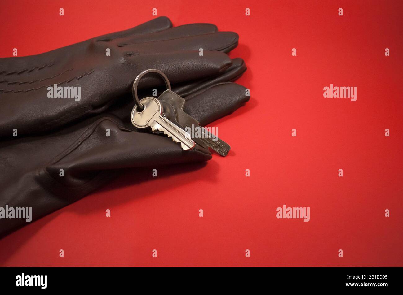 muestra guantes y teclas sobre un fondo rojo, con espacio para texto Foto de stock