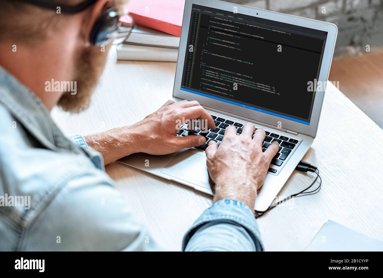 El programador de codificador de TI utiliza la codificación de escritura del ordenador portátil en la pantalla del portátil Foto de stock