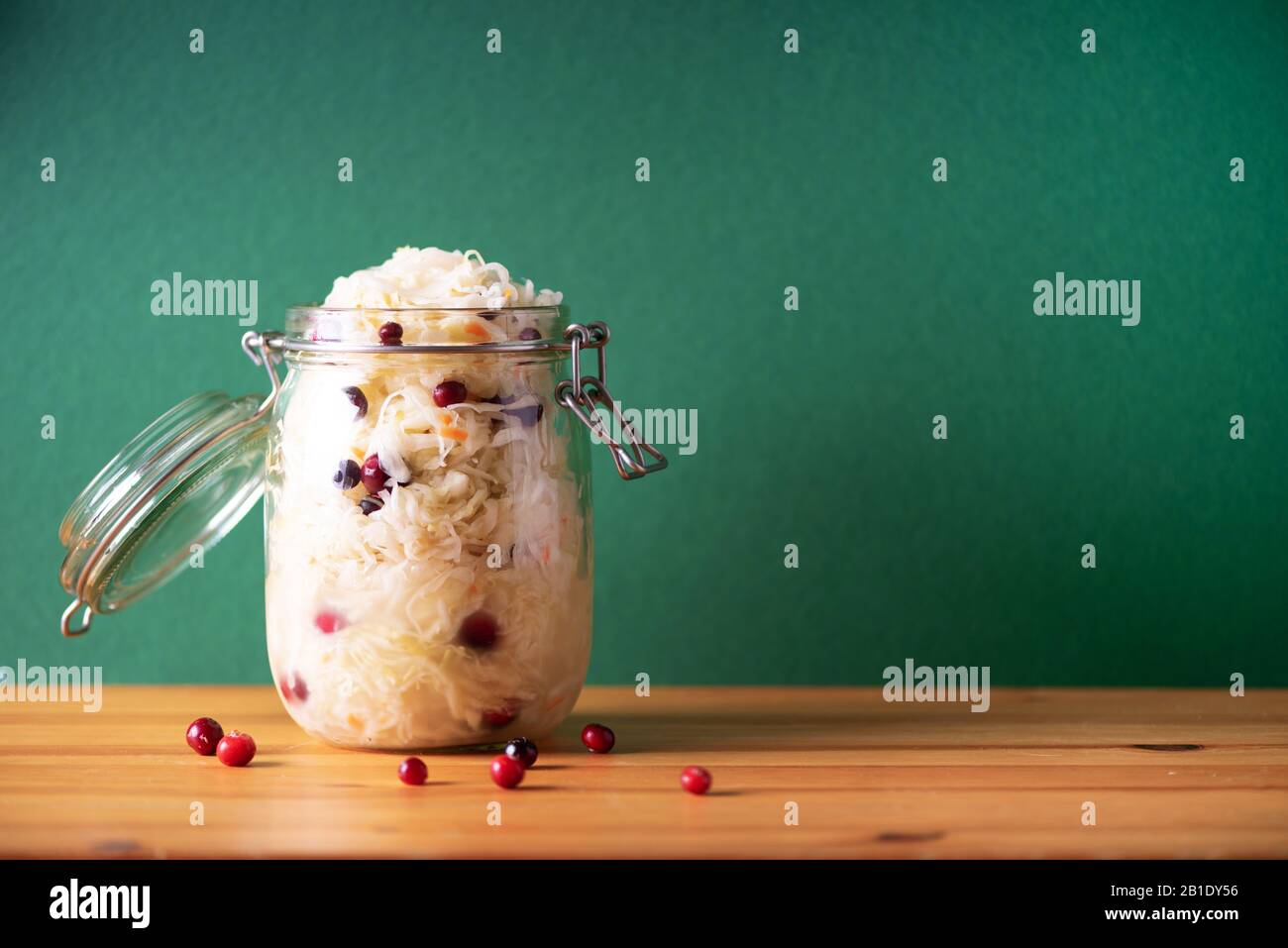 Un vaso de kéfir y granos de kéfir en un colador sobre un frasco de vidrio  sobre una tabla de cortar de madera enfoque selectivo el concepto de  alimentación saludable