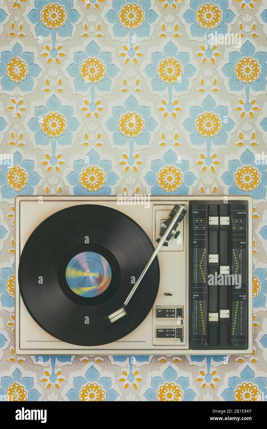 Imagen de estilo retro de un viejo reproductor de discos en la parte superior del fondo de pantalla de flores Foto de stock