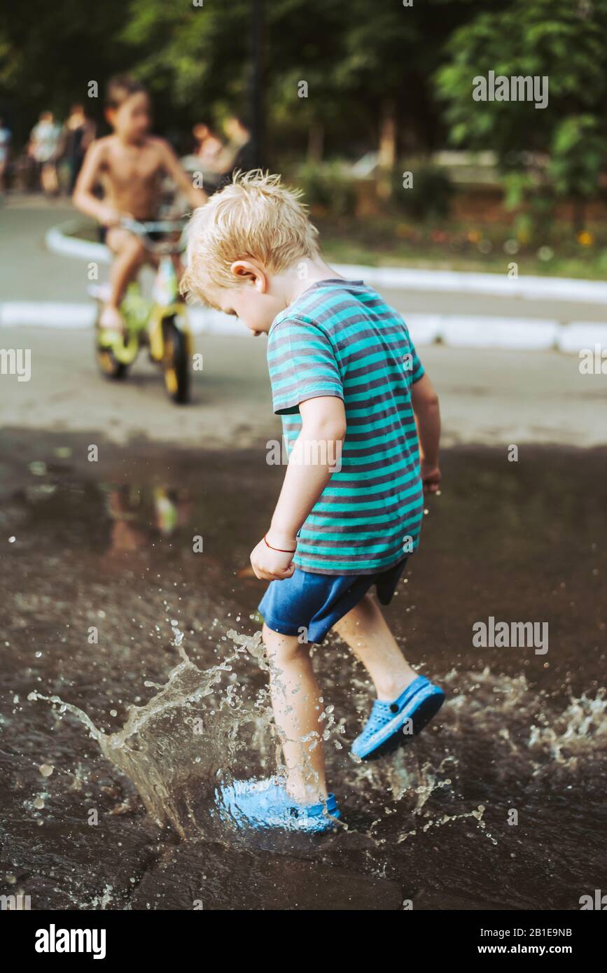 Niño saltando en un charco de lodo fotografías e imágenes de alta