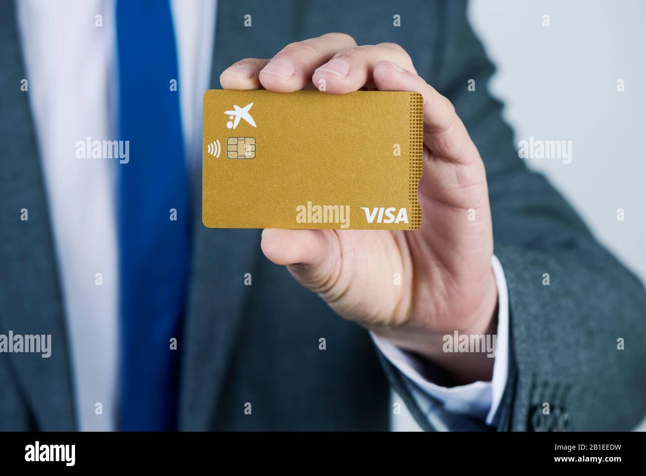 Barcelona, ESPAÑA - 13 DE FEBRERO de 2020: Un hombre de negocios, en un  elegante traje gris, muestra una tarjeta de crédito Visa Gold de CaixaBank  Fotografía de stock - Alamy