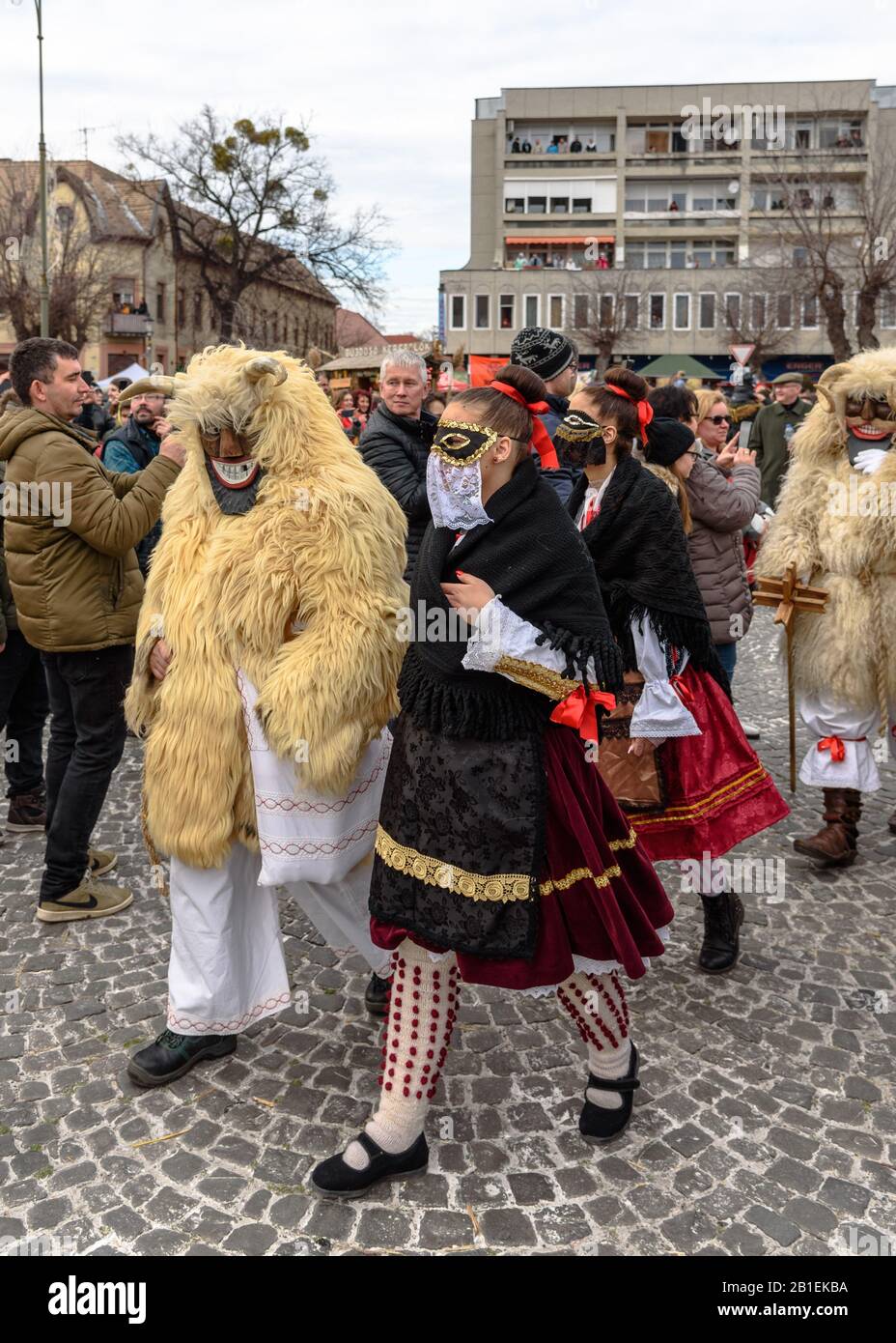 una buso enmascarada y una mujer vestida tradicionalmente caminando en la procesión en la celebración del carnaval de 2020 en Mohacs, Hungría Foto de stock