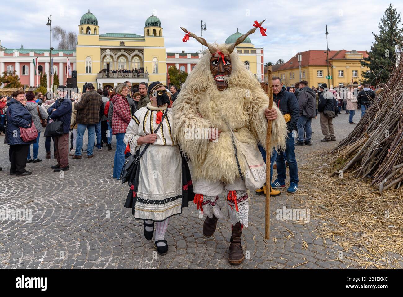 una buso enmascarada y una mujer vestida tradicionalmente caminando en la procesión en la celebración del carnaval de 2020 en Mohacs, Hungría Foto de stock
