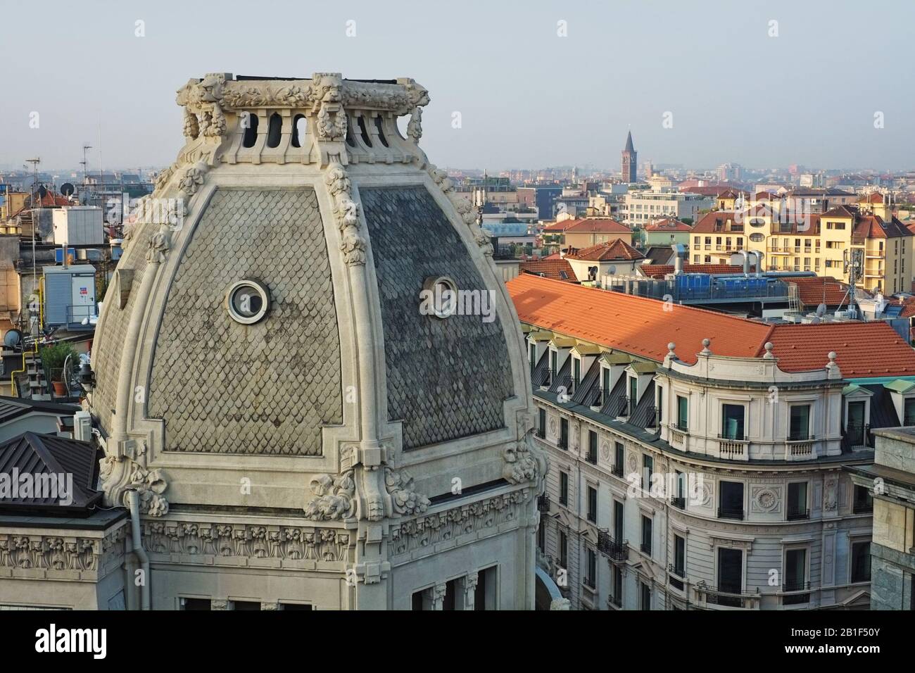 Una vista cercana de la cúpula de techo balaustrada del Palazzo Meroni - leones y guirnaldas florales, ventanas de óculos y la ciudad de Milán en el fondo Foto de stock