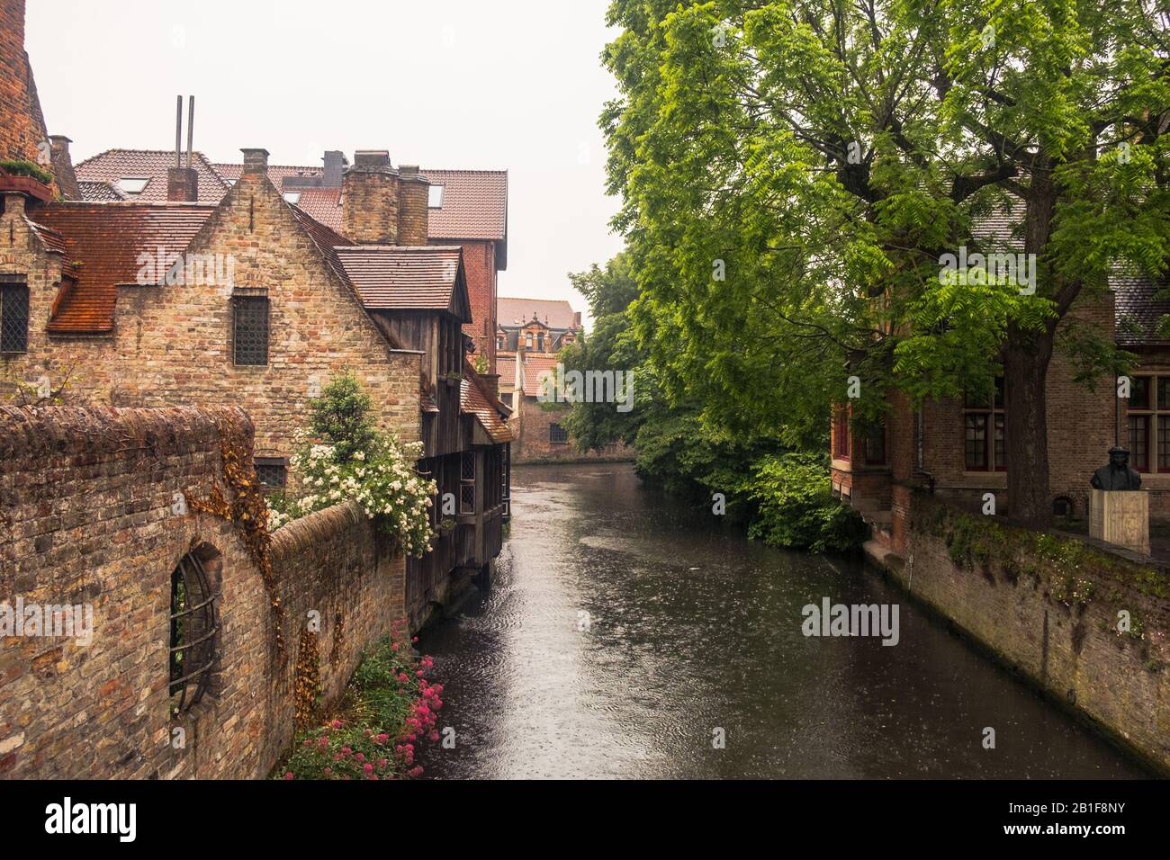 El Bonifaciusbridge ofrece vistas románticas a un canal y a las antiguas casas de Brujas. La lluvia torrencial lo hace completo: Esto es Bélgica. Foto de stock