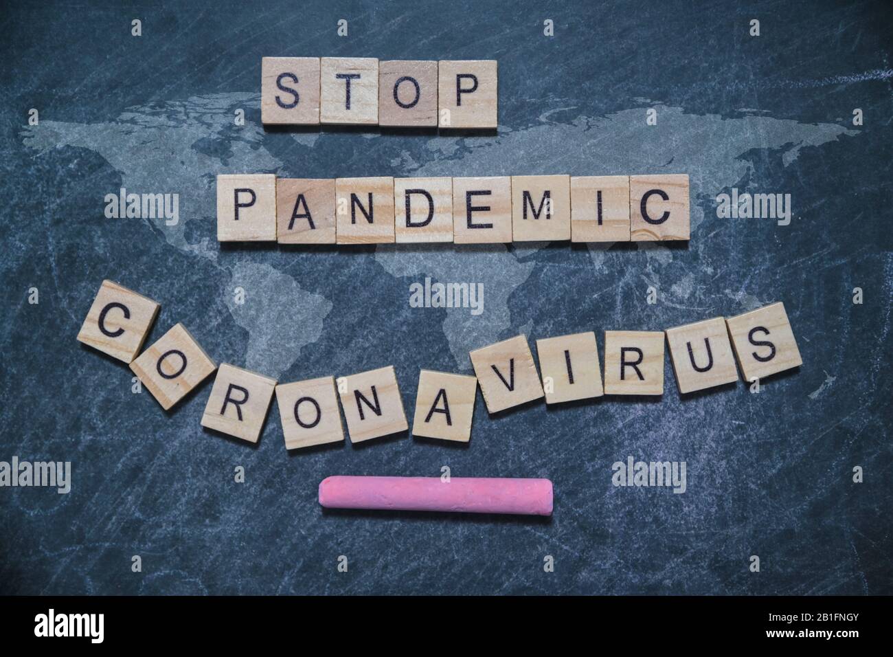 Detener la pandemia de corona virus palabra escrita bloque de madera. En el tablero negro con mapa del mundo calk escrito para su deseo, vista superior. Foto de stock