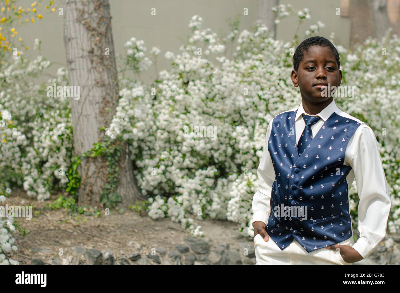 Niño negro, camisa blanca, corbata y chaleco azul Foto de stock