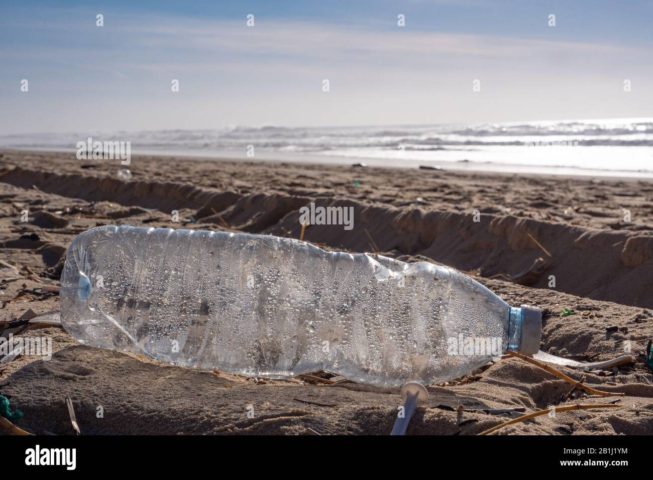 Botella de plástico en la playa, contaminación Foto de stock