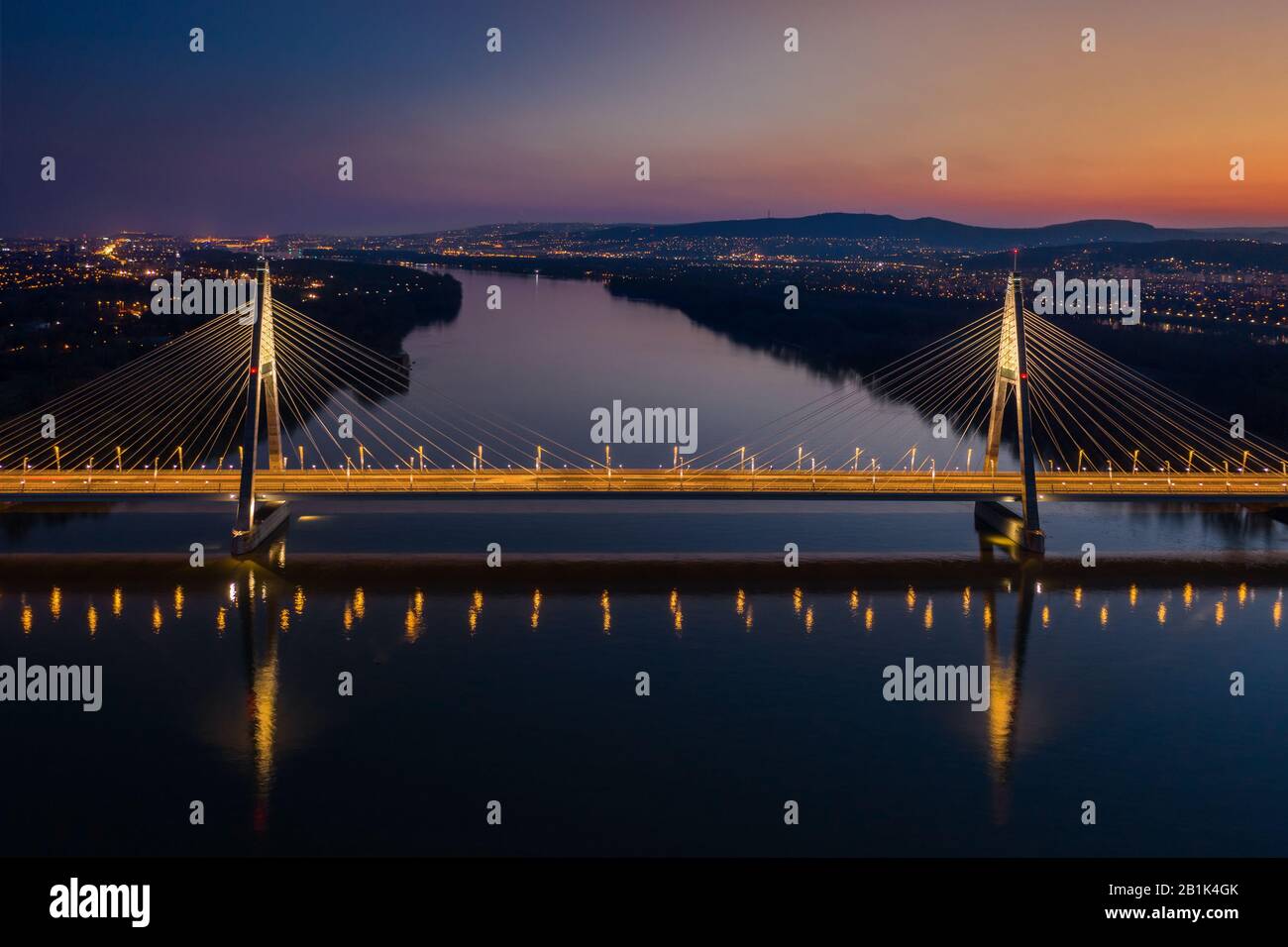 Budapest, Hungría - vista aérea de la hermosa alojamos Megyeri cable puente sobre el río Danubio, con cielo azul y naranja después del atardecer Foto de stock