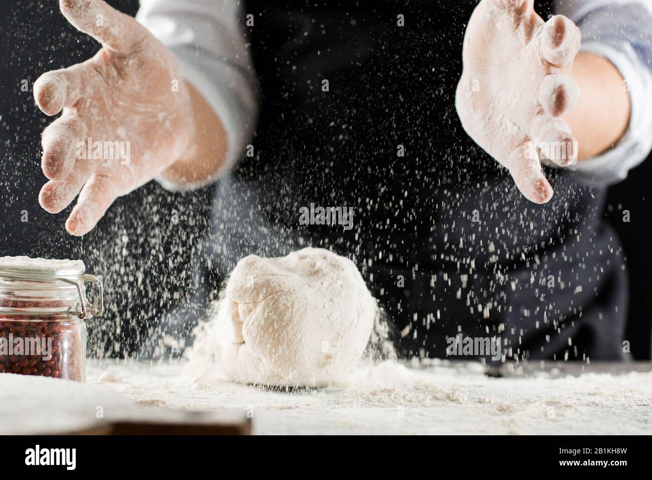 Cocine la masa de amasar con harina en la mesa de la cocina para detener el movimiento Foto de stock