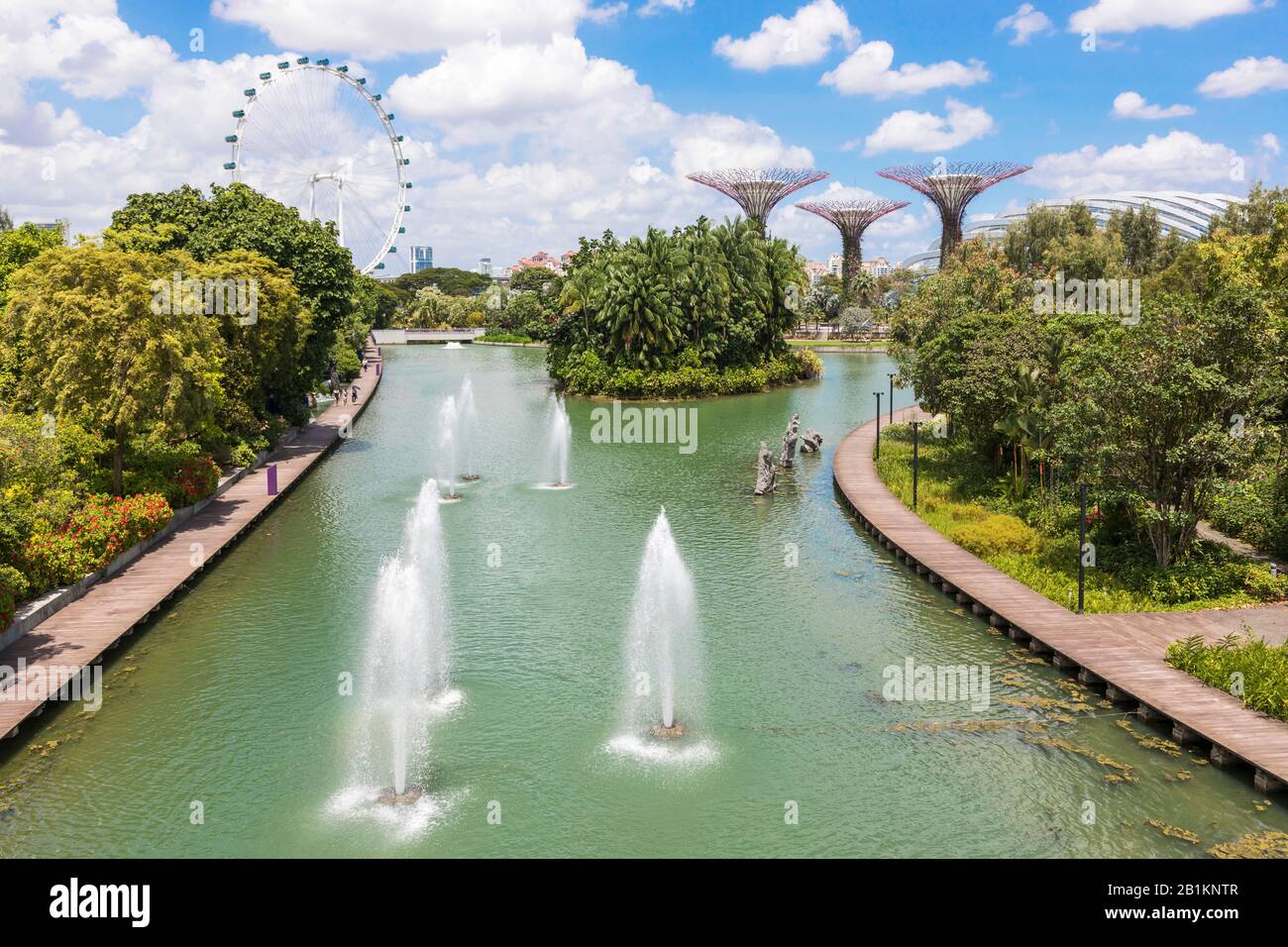 Fuentes de agua en el parque público, Jardines en la Bahía con el Singapore Flyer y rascacielos en el horizonte, Singapur, Asia Foto de stock