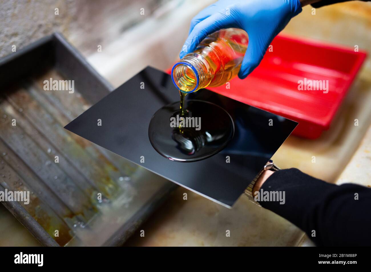 Fotógrafo que vierte la solución de colodion en la placa de hierro negro. Proceso de coloquio de placas húmedas. Foto de stock
