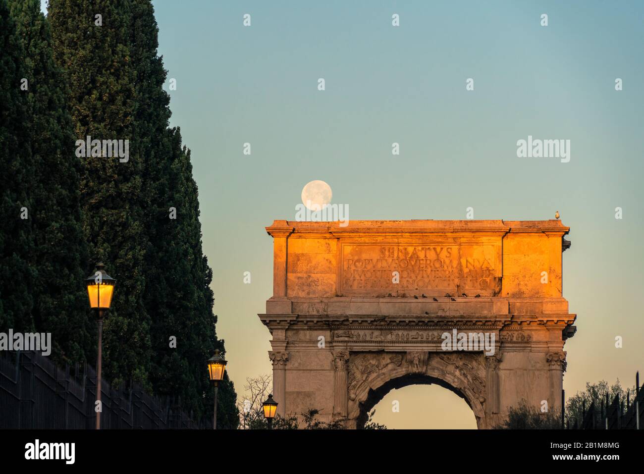 Luna llena al amanecer sobre el arco triunfal Arco di Tito, los Fora Imperiales, Roma, Lazio, Italia Foto de stock