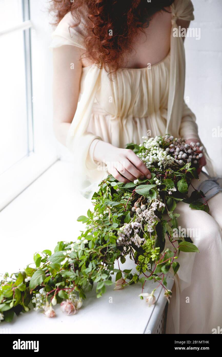 Mujer de la cosecha en elegante vestido blanco de la boda con ramo grande  de flores blancas pequeñas y follaje verde parado entre cortinas de color  pastel transparentes Fotografía de stock -