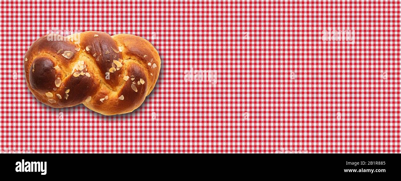 Pan dulce, tsoureki pascual, cozonac sobre fondo de mantel de cuadros rojos. Brioche trenzado, challah tradicional festivo. Banner, espacio de copia Foto de stock