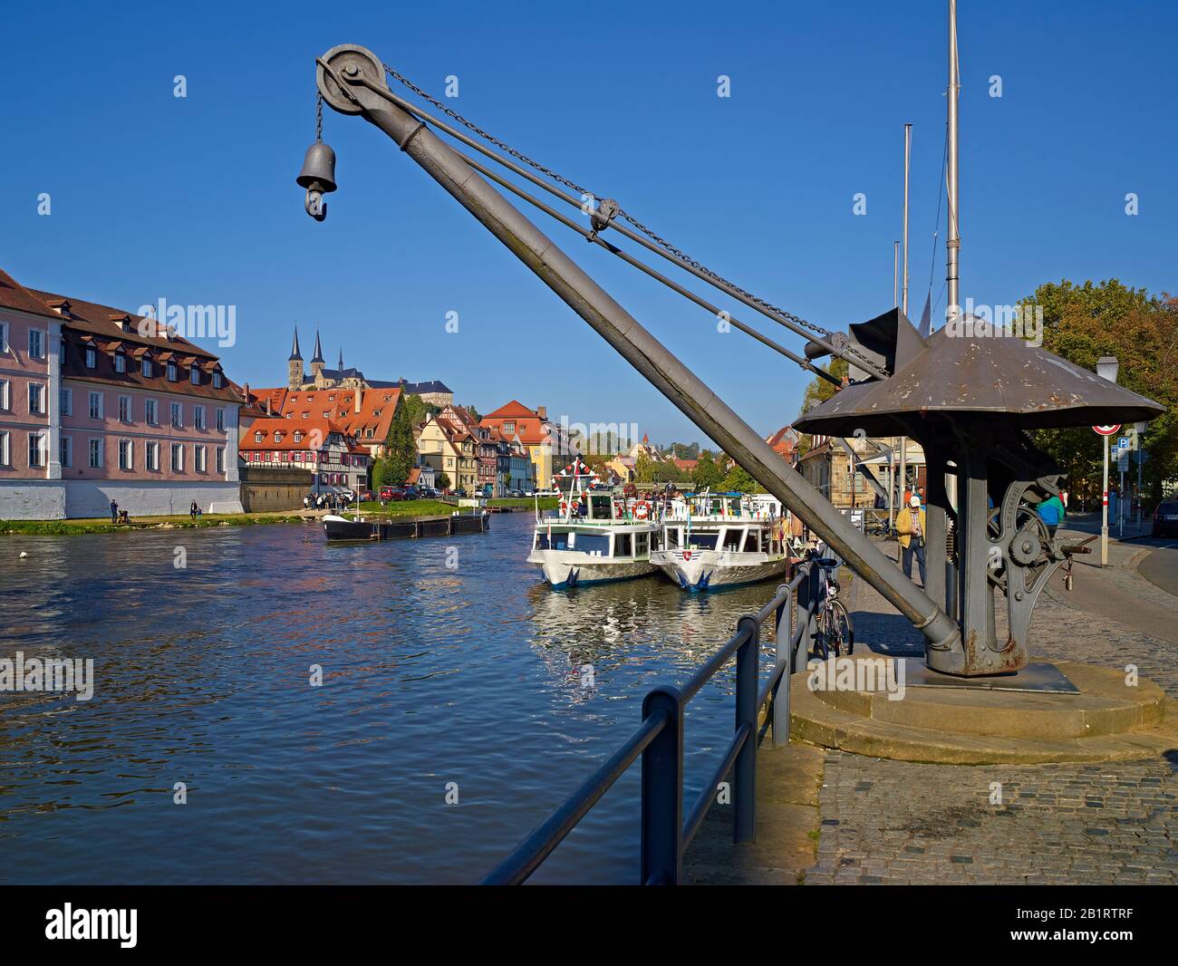 Antigua grúa de carga y barcos de excursión en el Regnitz en Bamberg, Alta Franconia, Baviera, Alemania Foto de stock