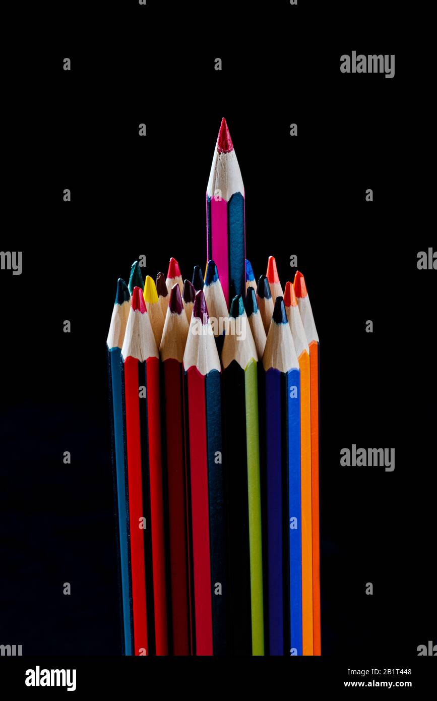 Grupo de lápices con uno saliendo del grupo, impar uno fuera. Lápices de colores. Foto de stock