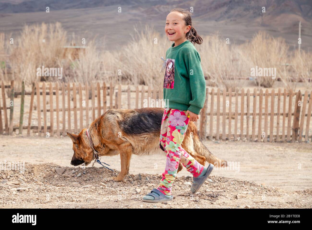 Mongolia Ulgii 2019-05-05 joven mongol sonriente con ropa colorida con un  perro pastor caucásico en el fondo de la valla, pueblo, montañas. Concepto  Fotografía de stock - Alamy