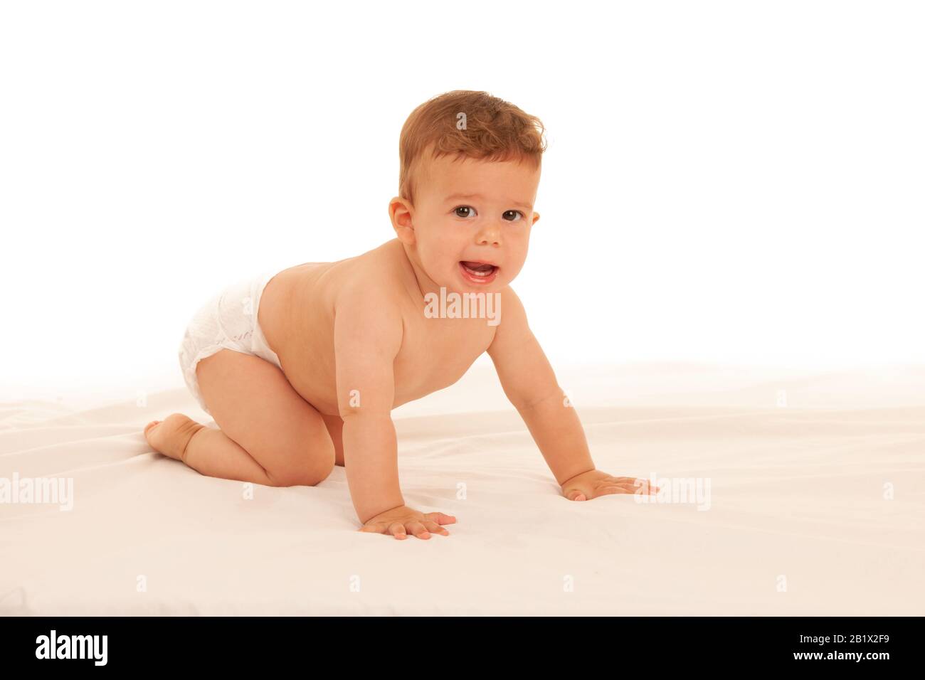 Un niño hapy jugando en la cama aislado sobre blanco Foto de stock