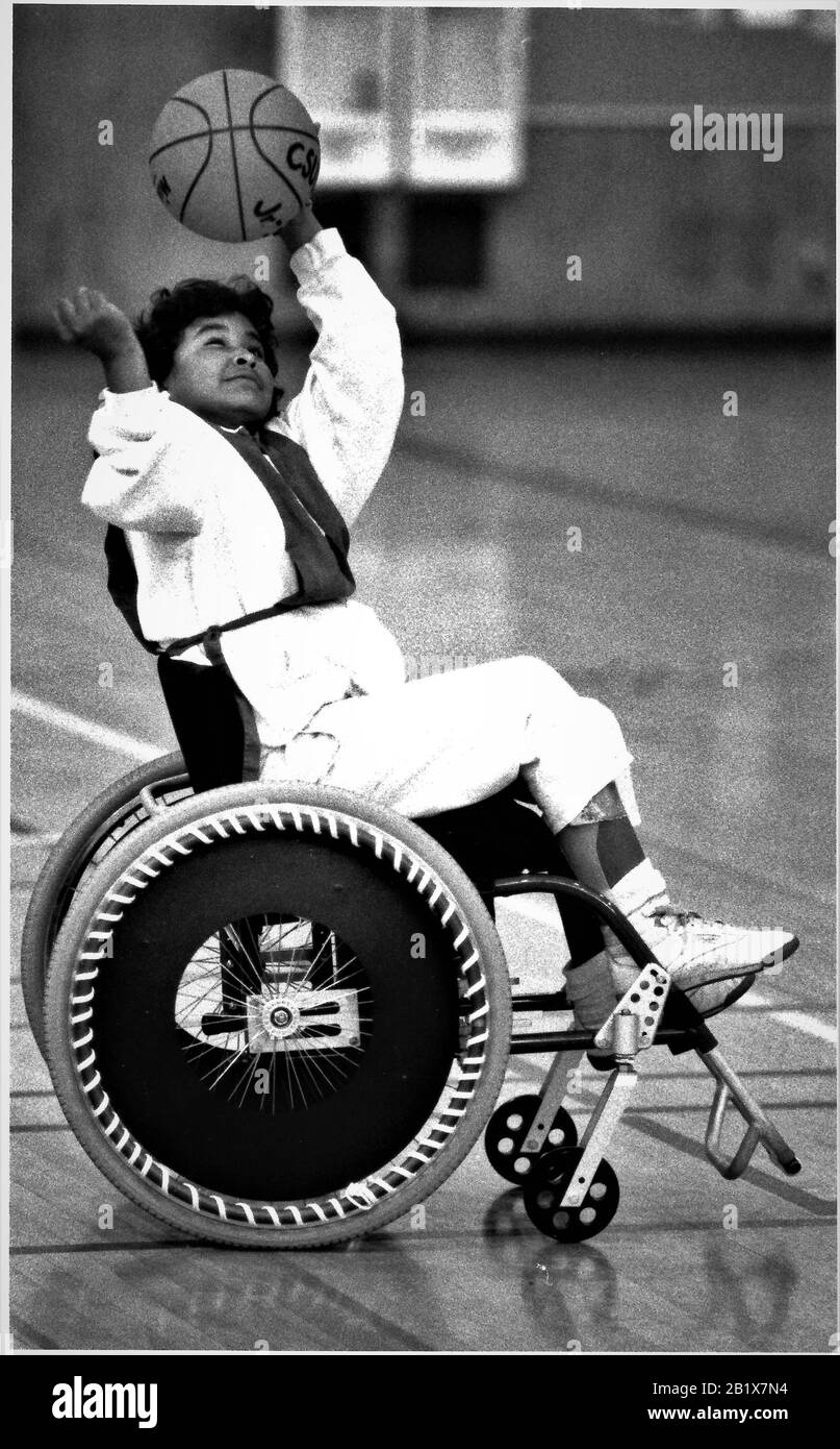 Joven hispana en silla de ruedas jugando deportes, baloncesto disparando para la canasta Foto de stock